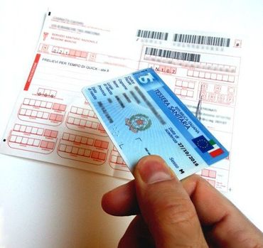 Mano che tiene una carta blu sopra una ricevuta di pagamento bianca con campi modulo e codici a barre rossi