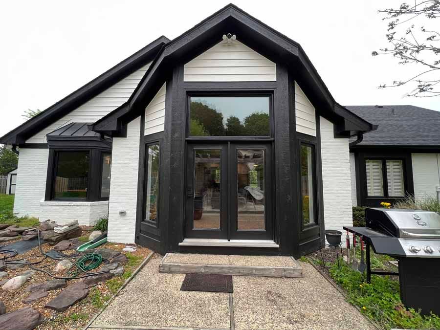 A black and white house with a grill in front of it