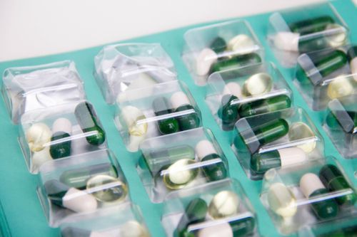 Pharmacist showing a pill organizer to a customer in a pharmacy.