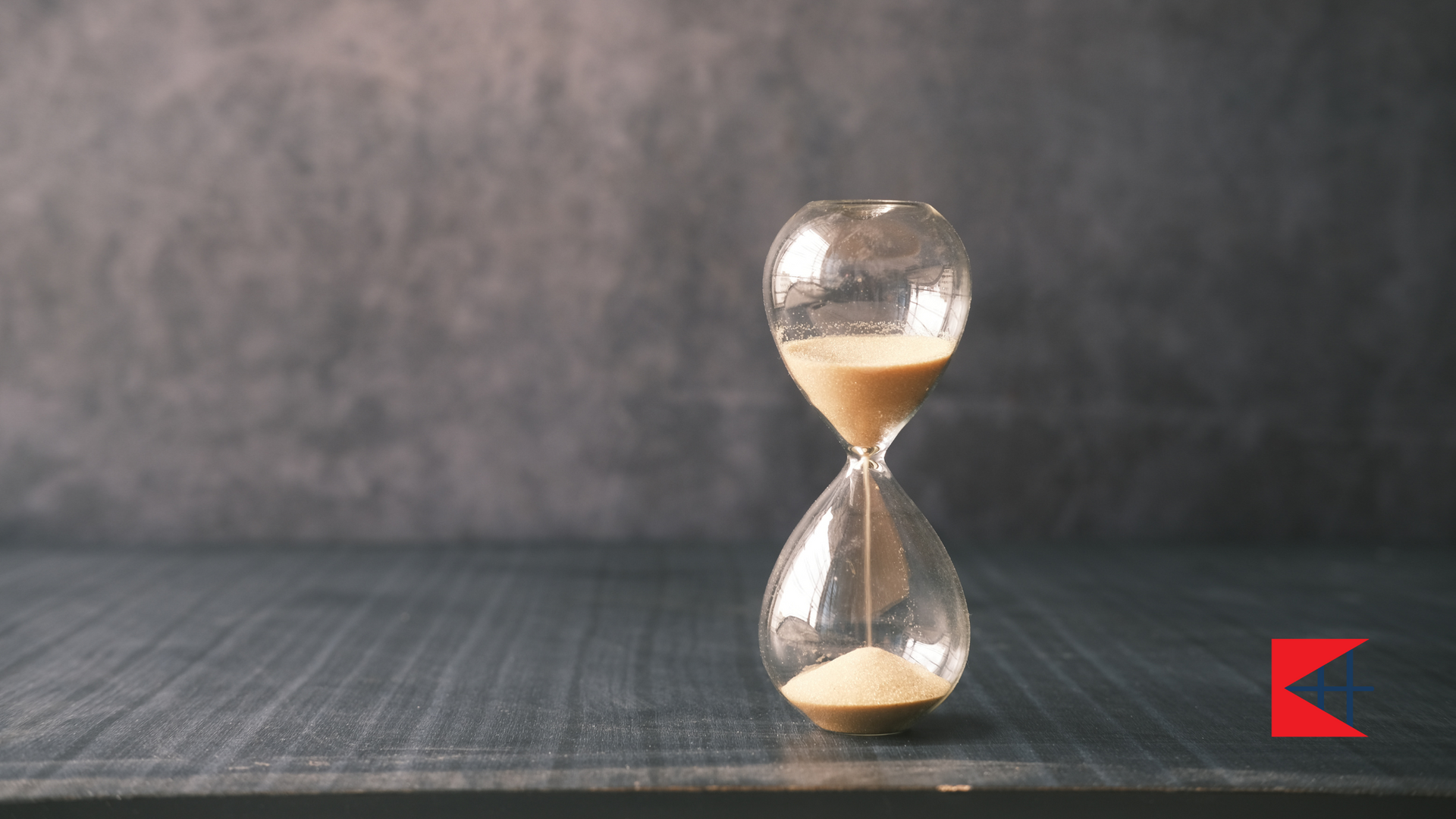 An hourglass is sitting on a wooden table.