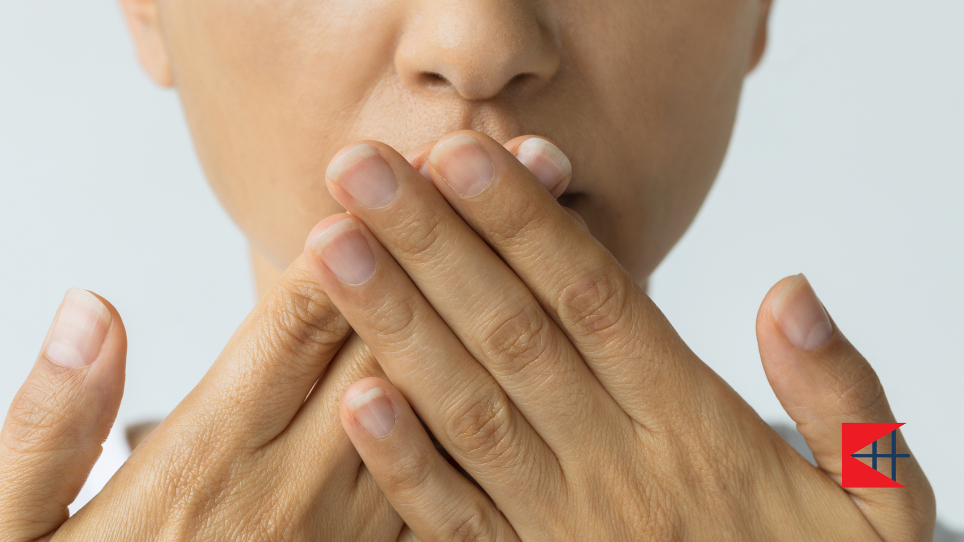 A woman is covering her mouth with her hands.