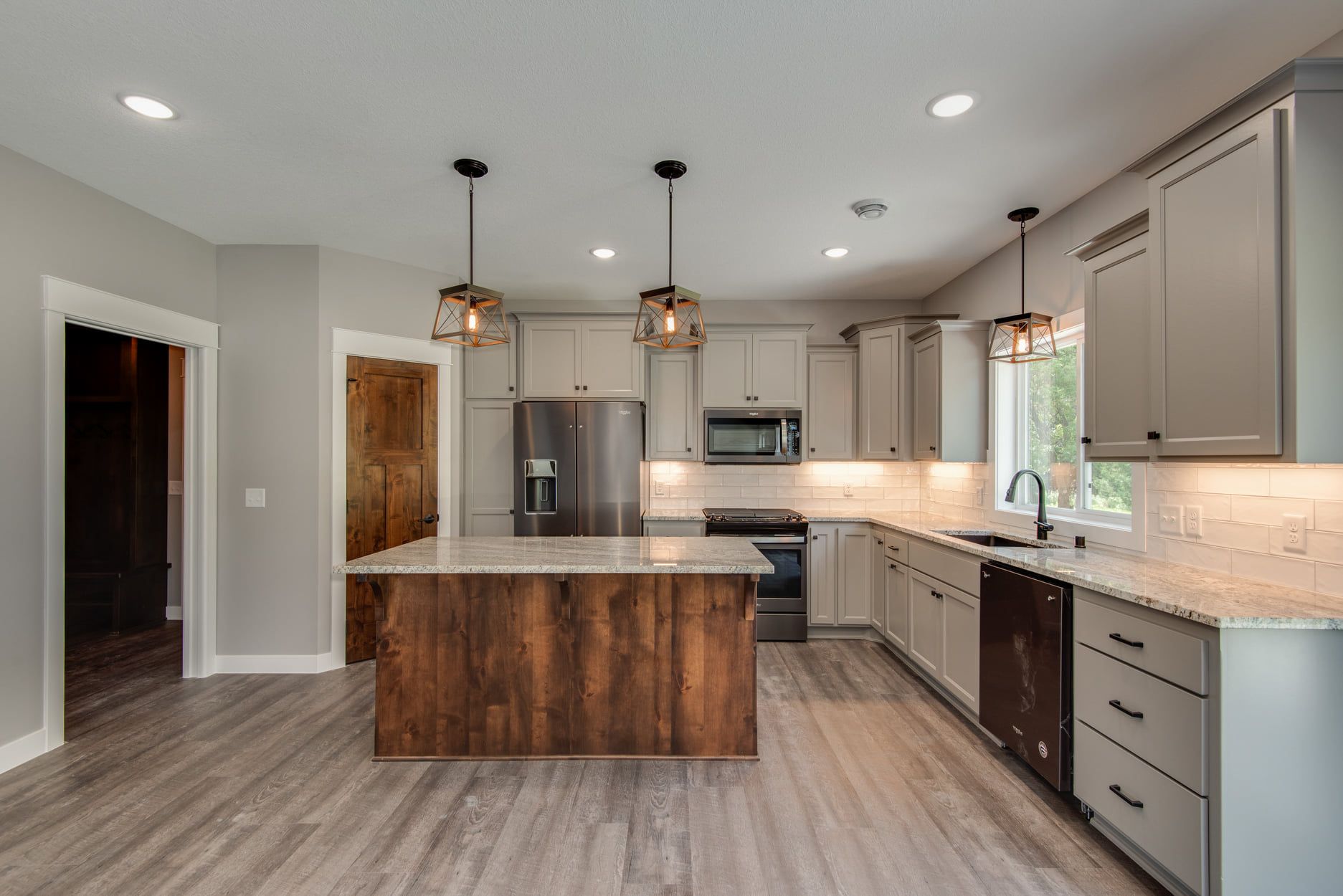 Modern kitchen with gray cabinets, wood island, granite countertops, stainless appliances, and pendant lights.