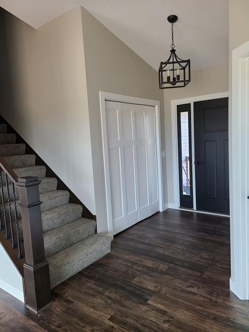 Entryway with carpeted stairs, white closet doors, dark wood floor, and a hanging lantern light fixture