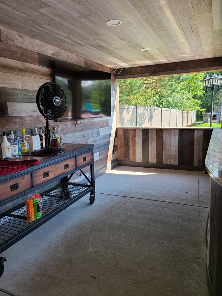 Covered patio with grill, fan, and stone bar overlooking a green yard