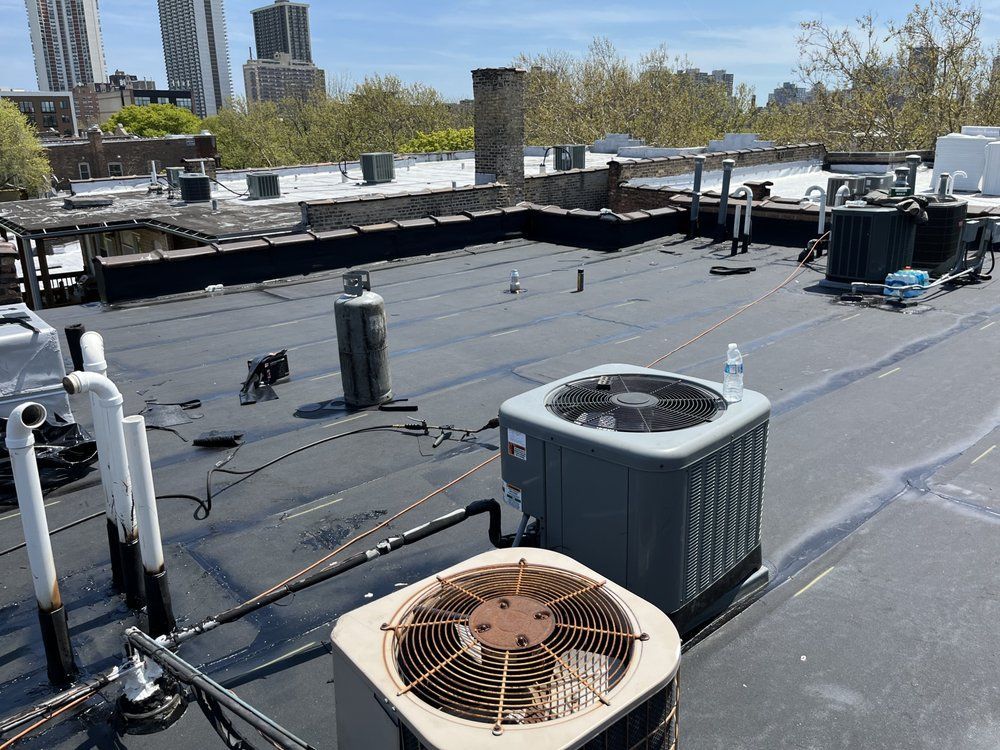 Flat commercial rooftop with HVAC units, vents, and city buildings in the background