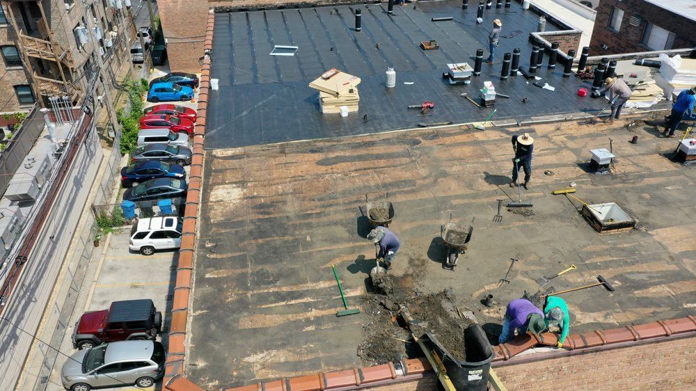 Workers repair a flat rooftop, with tools, materials, and parked cars visible below.