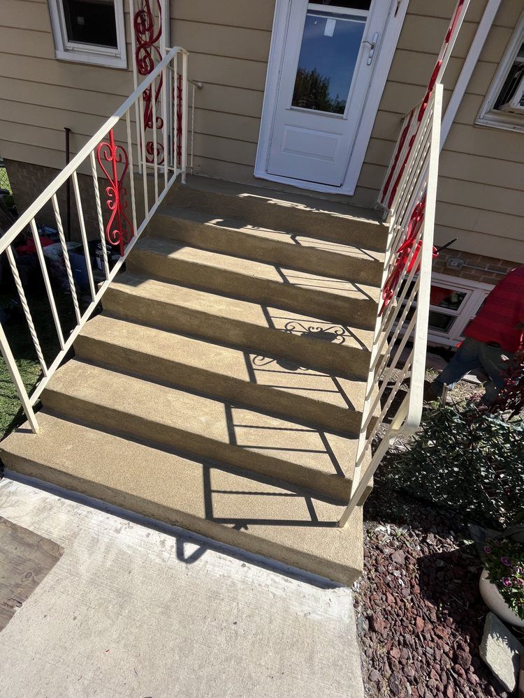 Front steps with red-and-white railings leading to a white door on a beige house