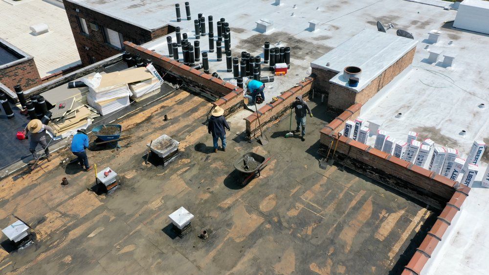 Rooftop construction site with workers, tools, and materials on a partially covered roof.