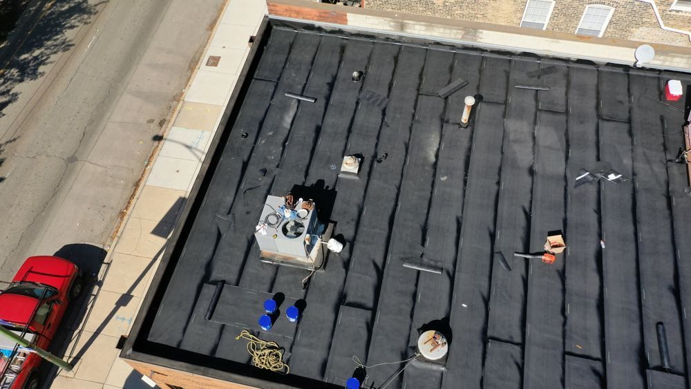 Aerial view of a dark rooftop with scattered equipment beside a street and parked cars.