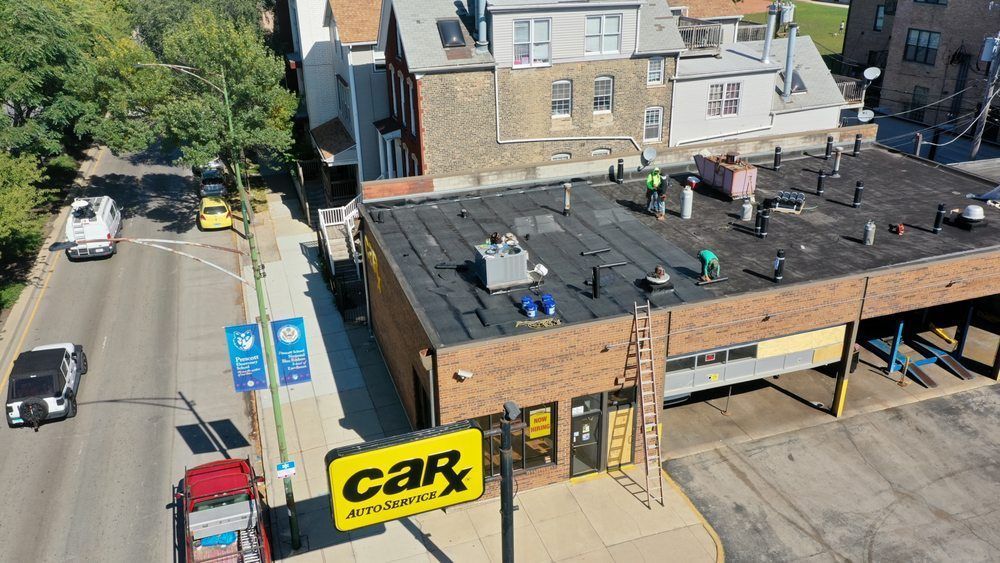 Aerial view of a car dealership beside a street, with yellow signage and parked cars.