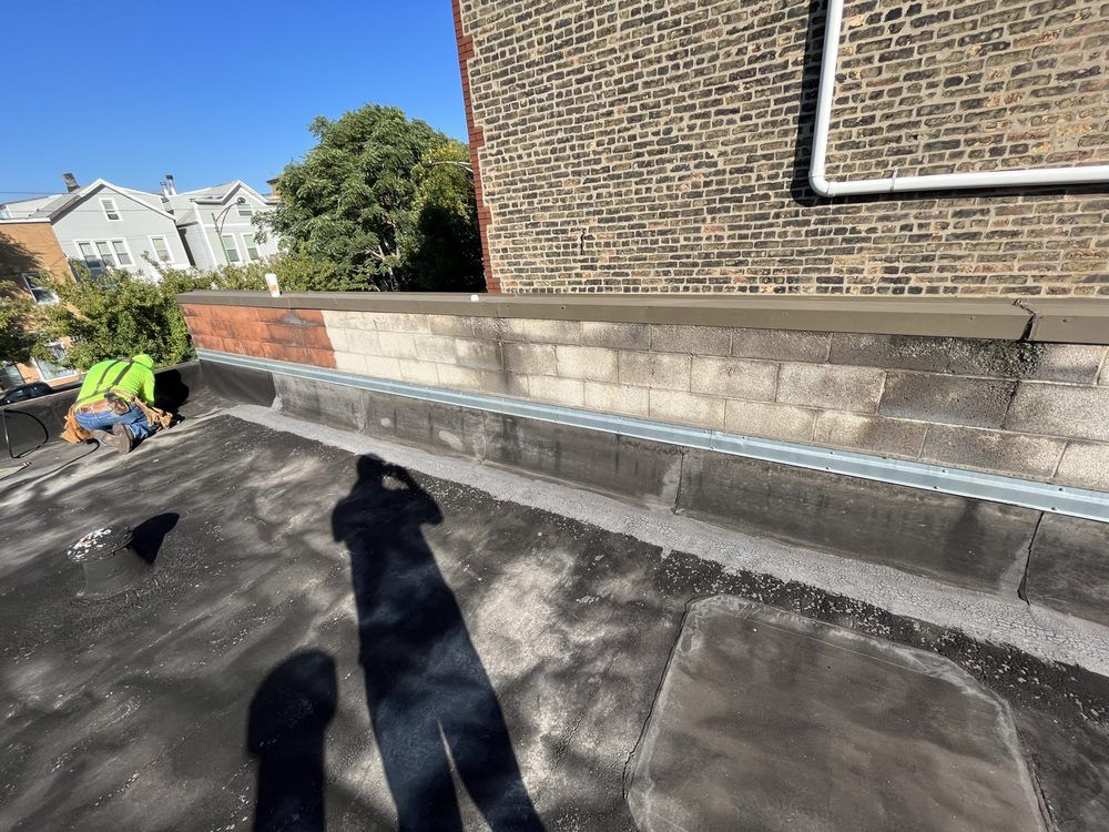 Worker inspecting rooftop next to brick wall and vent pipe on a sunny day