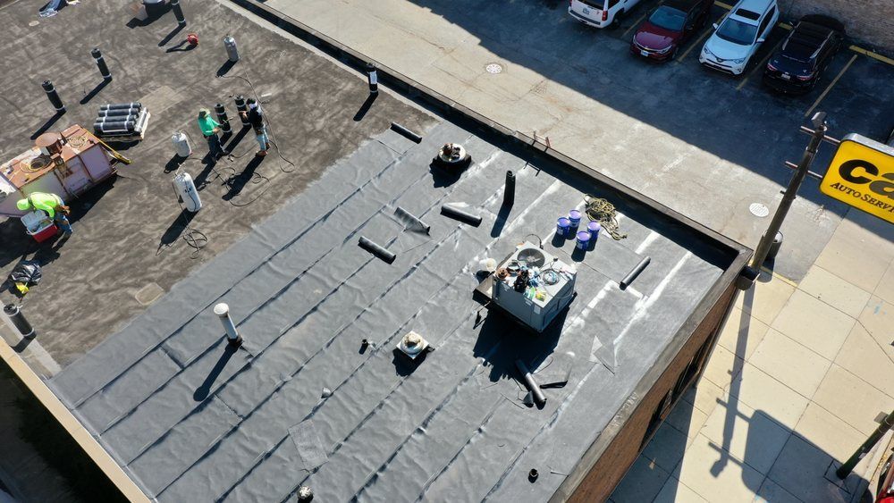 Rooftop with workers, tools, and equipment beside a street and parked cars below