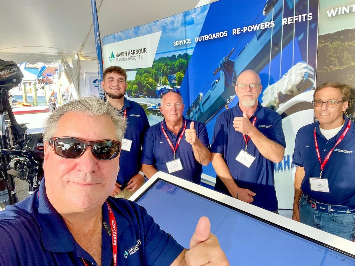 Group of employees pictured outside on a sunny summer day with boats in the background