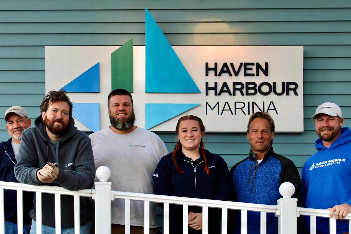 Group of employees pictured outside on a sunny summer day with boats in the background