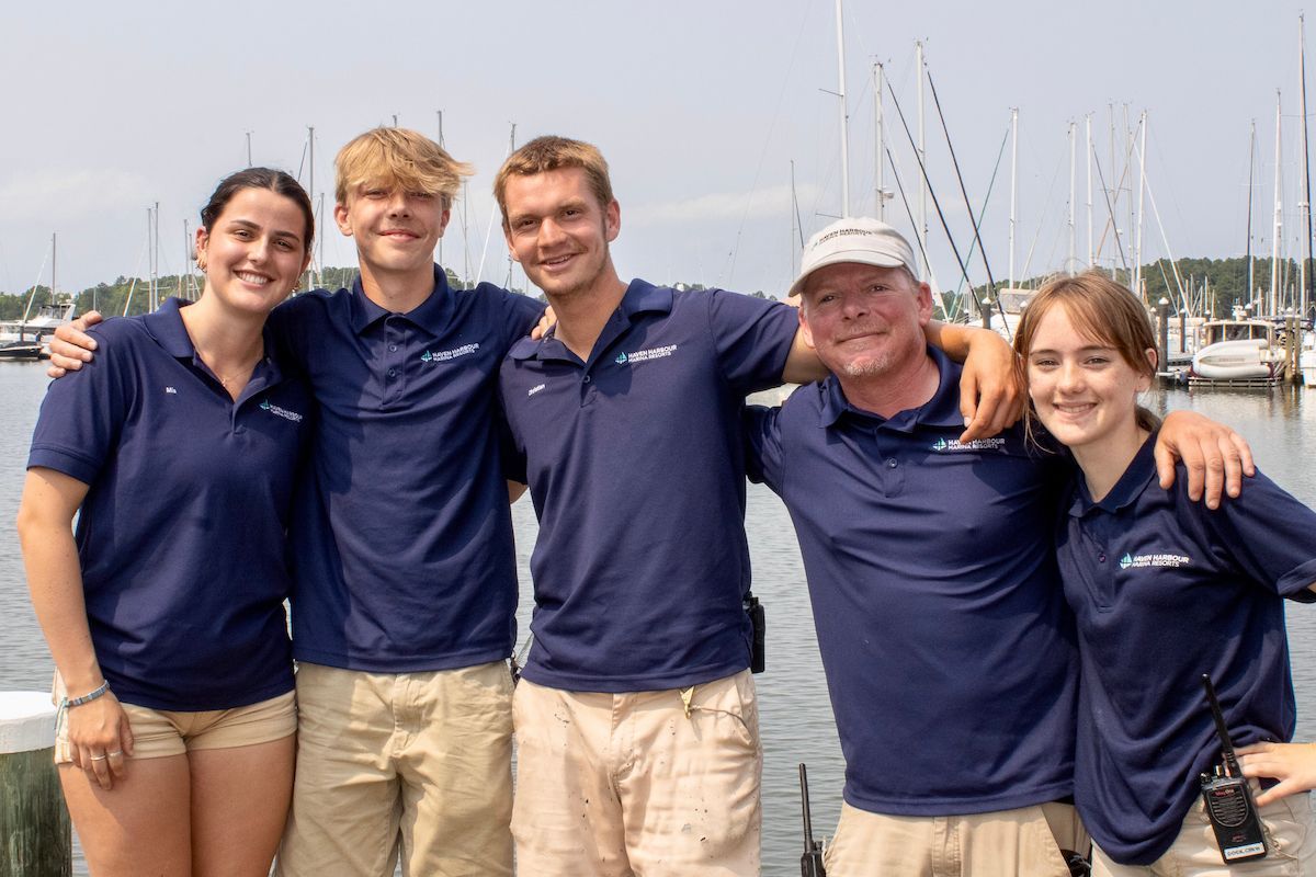 Group of employees pictured outside on a sunny summer day with boats in the background