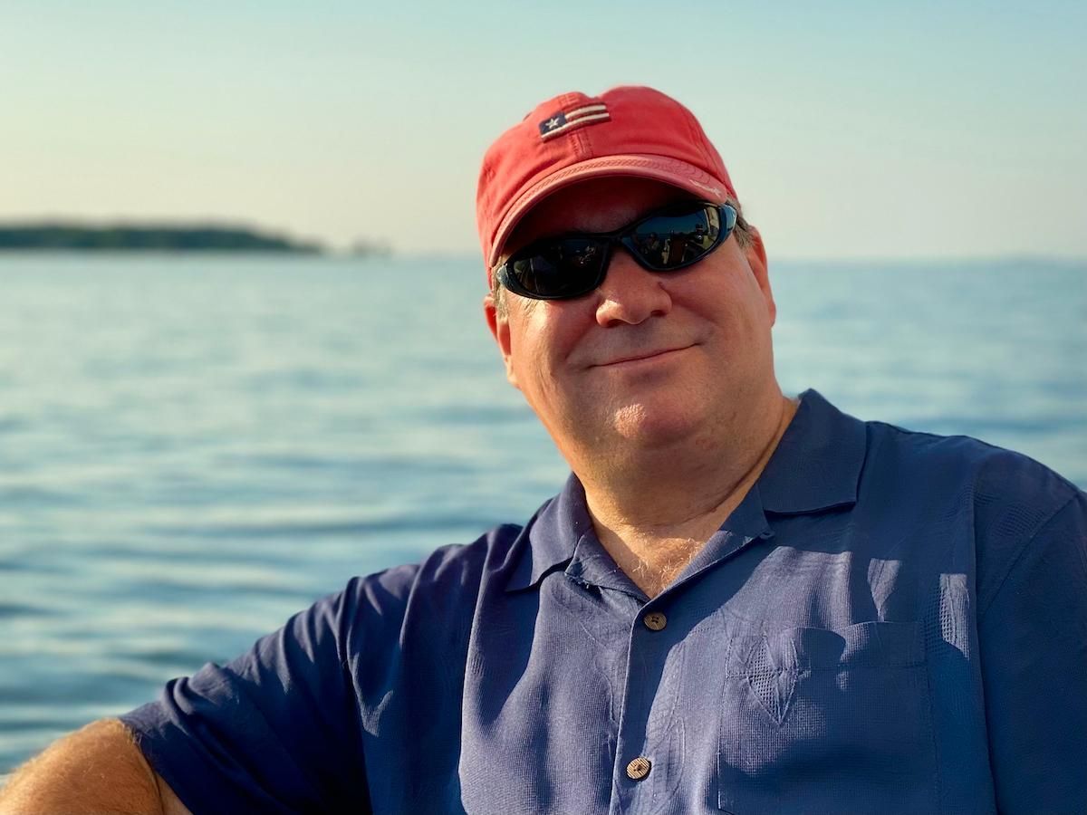 Man on boat posing for photo wearing sunglasses and hat