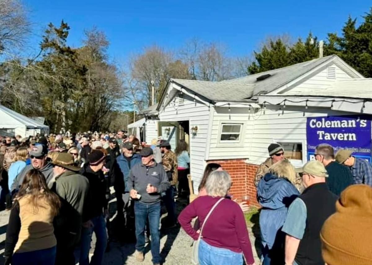 Large crowd gathered outside Coleman's Tavern, people are standing and socializing on a sunny day
