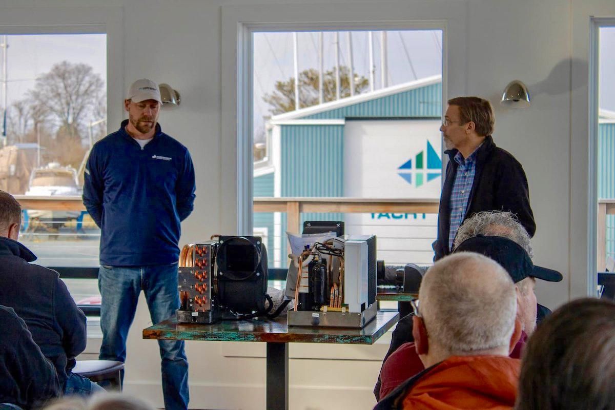 Two men presenting on boat maintenance topics in front of room of seated attendees