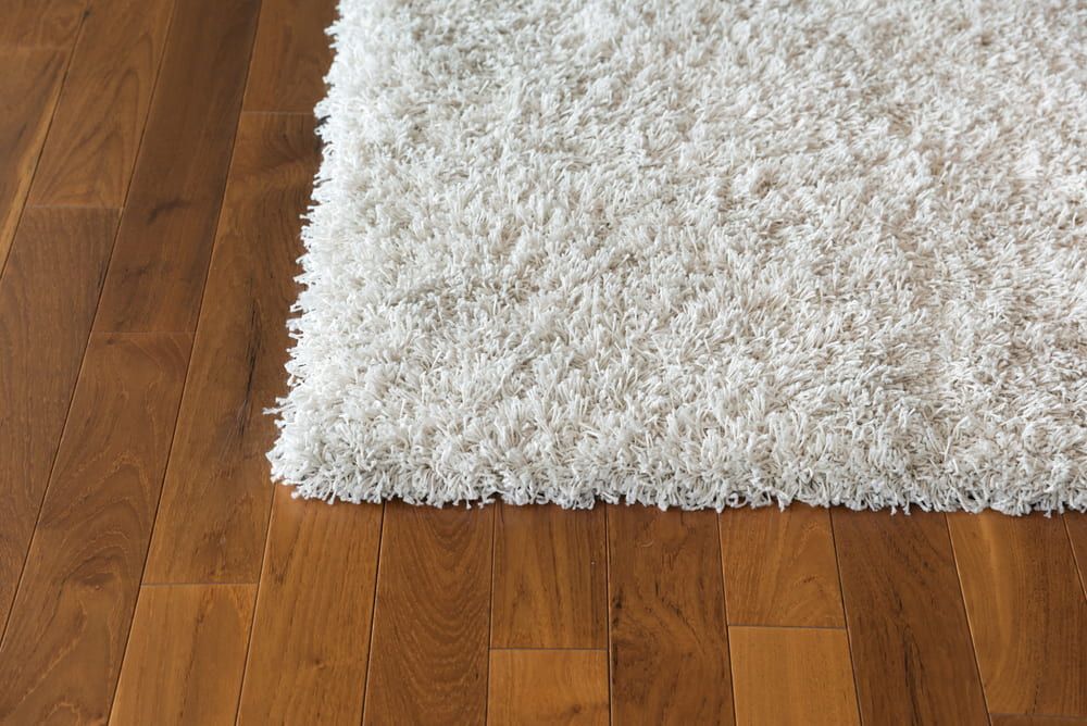 A White Rug is Sitting on a Wooden Floor — Clean Right Carpet Cleaning In Port Macquarie, NSW