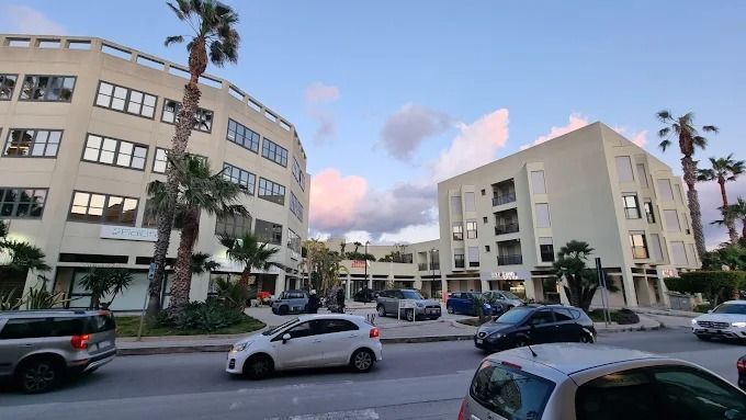 Veduta stradale di moderni palazzi residenziali con auto parcheggiate. La sede di Samo a Trapani