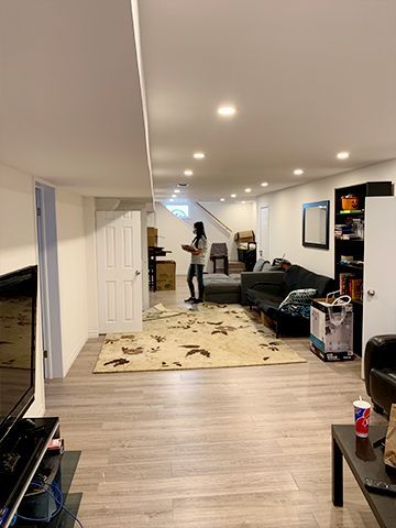 A woman is standing in a living room in a basement.