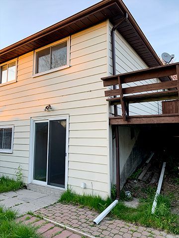 The back of a house with a sliding glass door and a wooden deck.