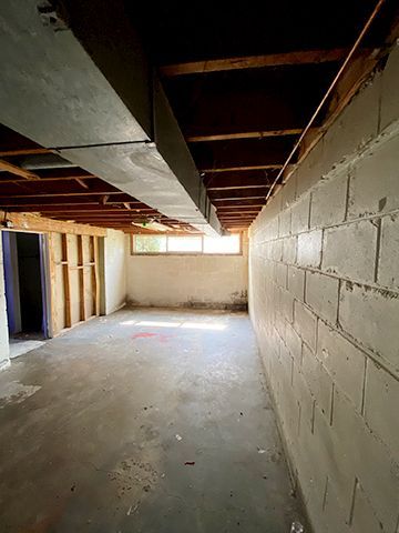 An empty basement with a brick wall and a window.