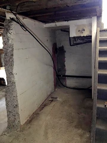 A basement with a broken wall and stairs.