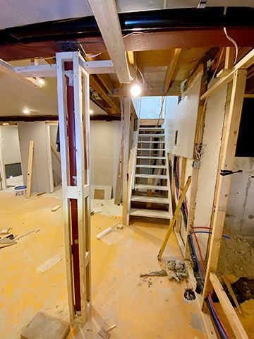 A staircase is being built in a basement under construction.