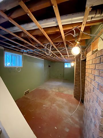 An empty basement with a brick wall and a window.