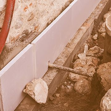 A concrete wall is being built next to a pile of rocks.