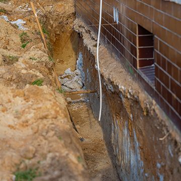 There is a hole in the ground next to a brick wall.