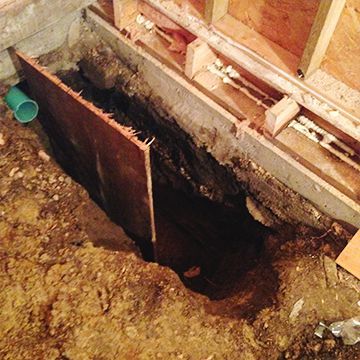 A hole in the ground with a green pipe coming out of it.