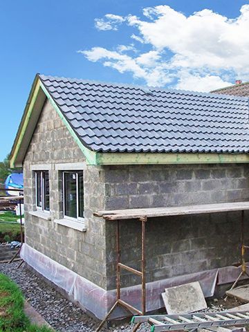A small brick house with a tiled roof is being built.