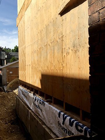 A building is being built with a lot of plywood on the side.