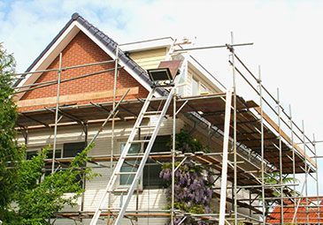 A house is being remodeled with scaffolding and a ladder.