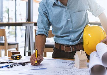 A man is holding a hard hat and writing on a piece of paper.