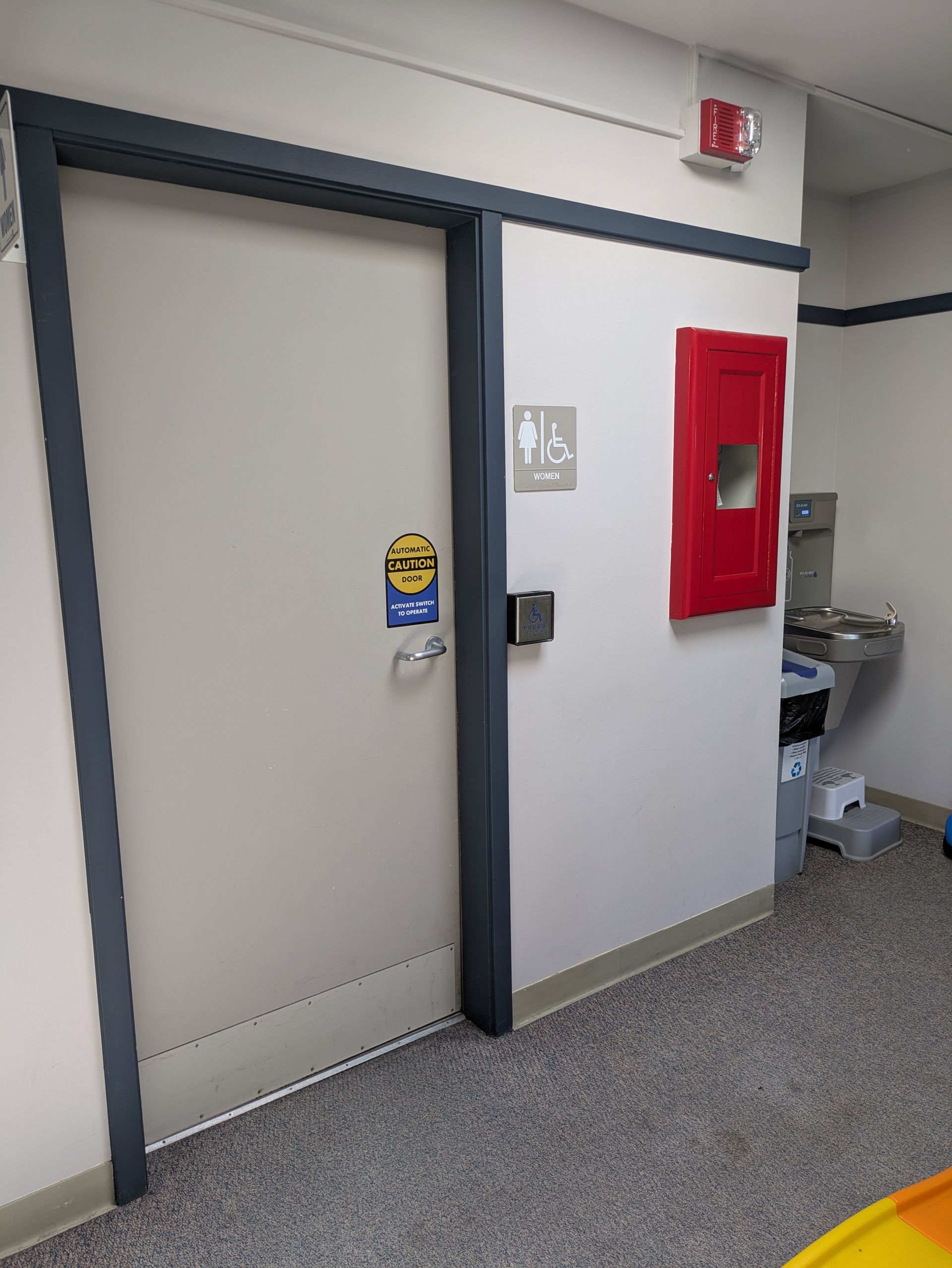 A bathroom with an ADA door button.