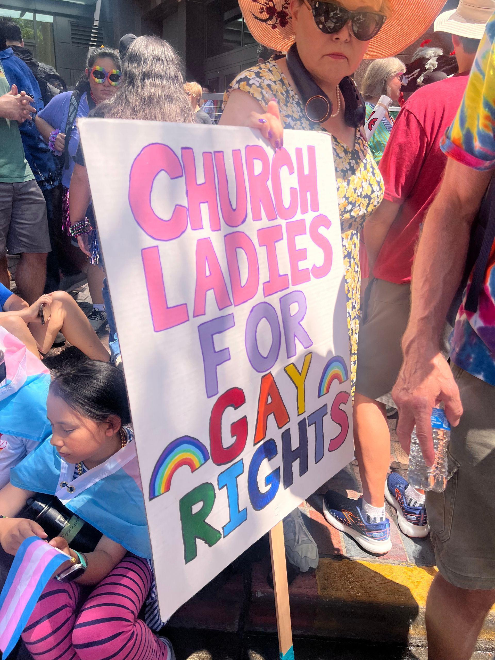 Protest sign reading “Church Ladies for Gay Rights” held among a crowd at a street march.