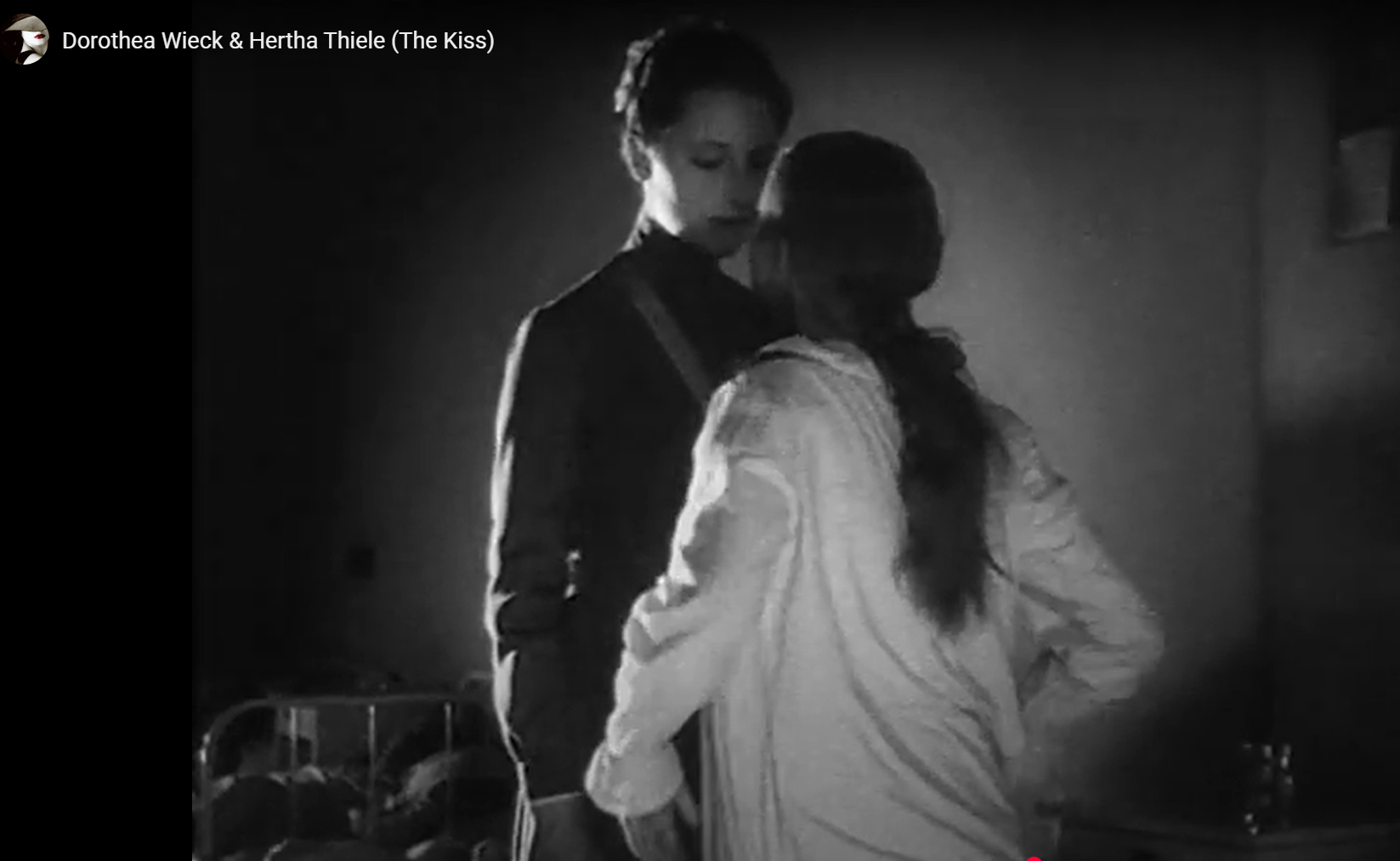 Two people standing close in a dim black-and-white room, facing each other in a tense moment