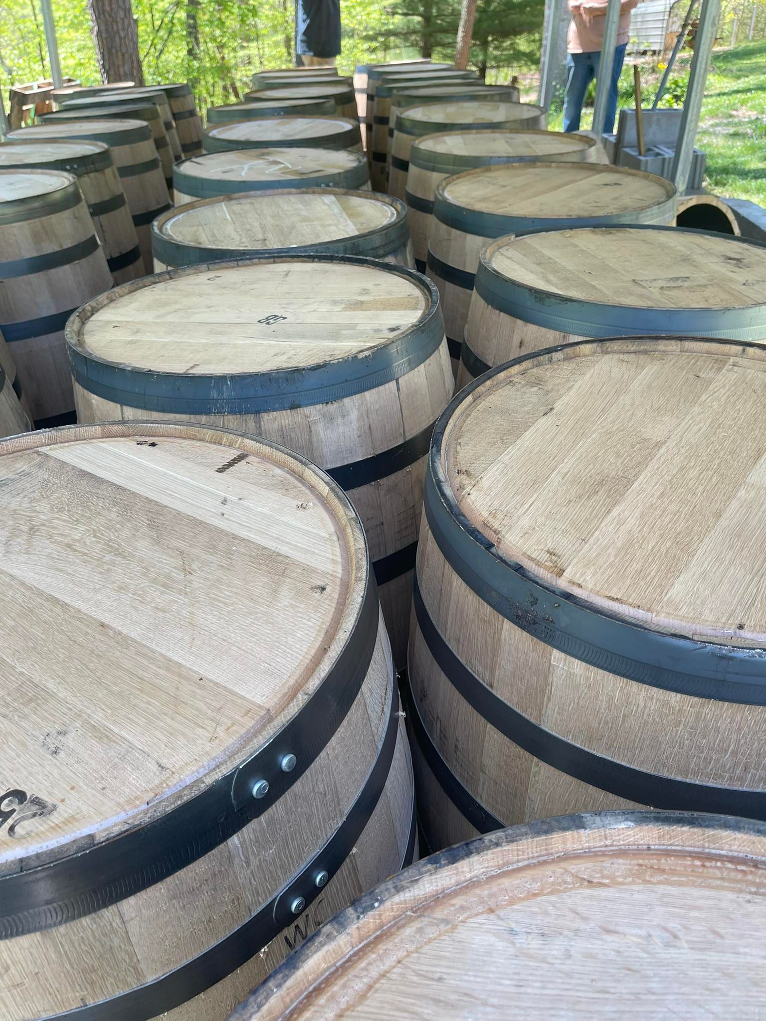 Wooden barrels stacked outdoors, featuring metal bands, for aging.