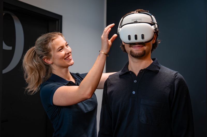 Medewerker Revital ondersteund een deelnemer tijdens een VR-oefening