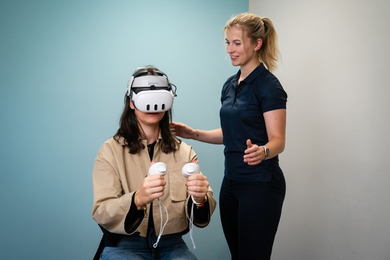 Medewerker Revital begeleidt een deelnemer tijdens een VR-sessie