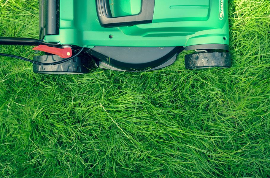 A green lawn mower positioned on a patch of lush green grass.
