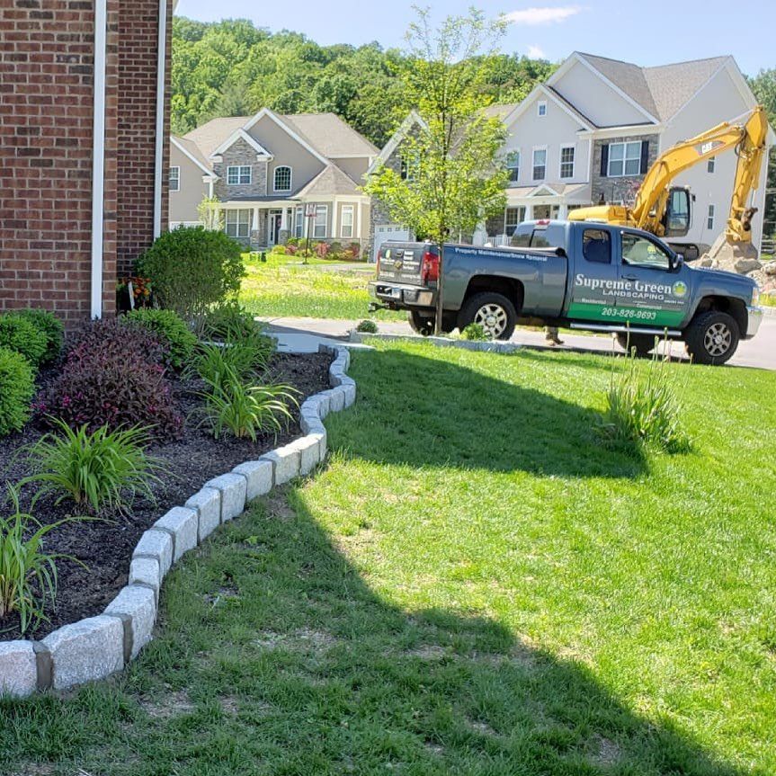 A truck is parked in the grass in front of a house.