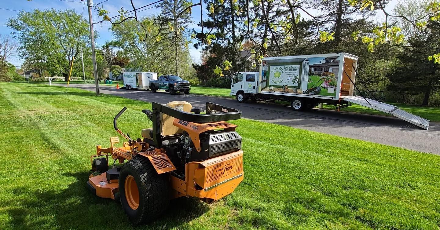 A lawn mower is parked in the grass next to a truck.