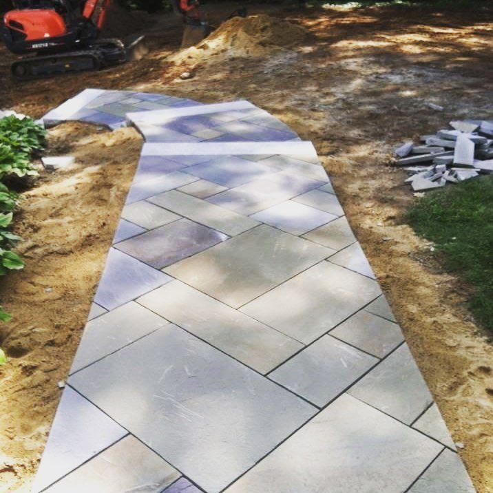 A stone walkway is being built in a backyard