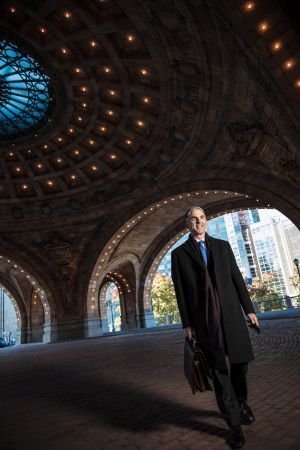 A man in a suit and tie is carrying a briefcase under a dome.
