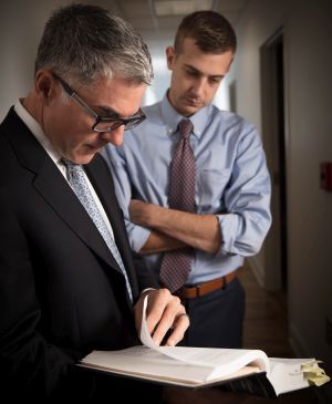 Two men in suits and ties are looking at a book