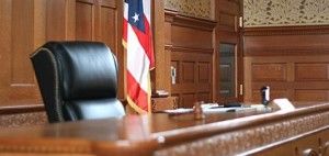 A judge 's chair in a courtroom with an american flag in the background.